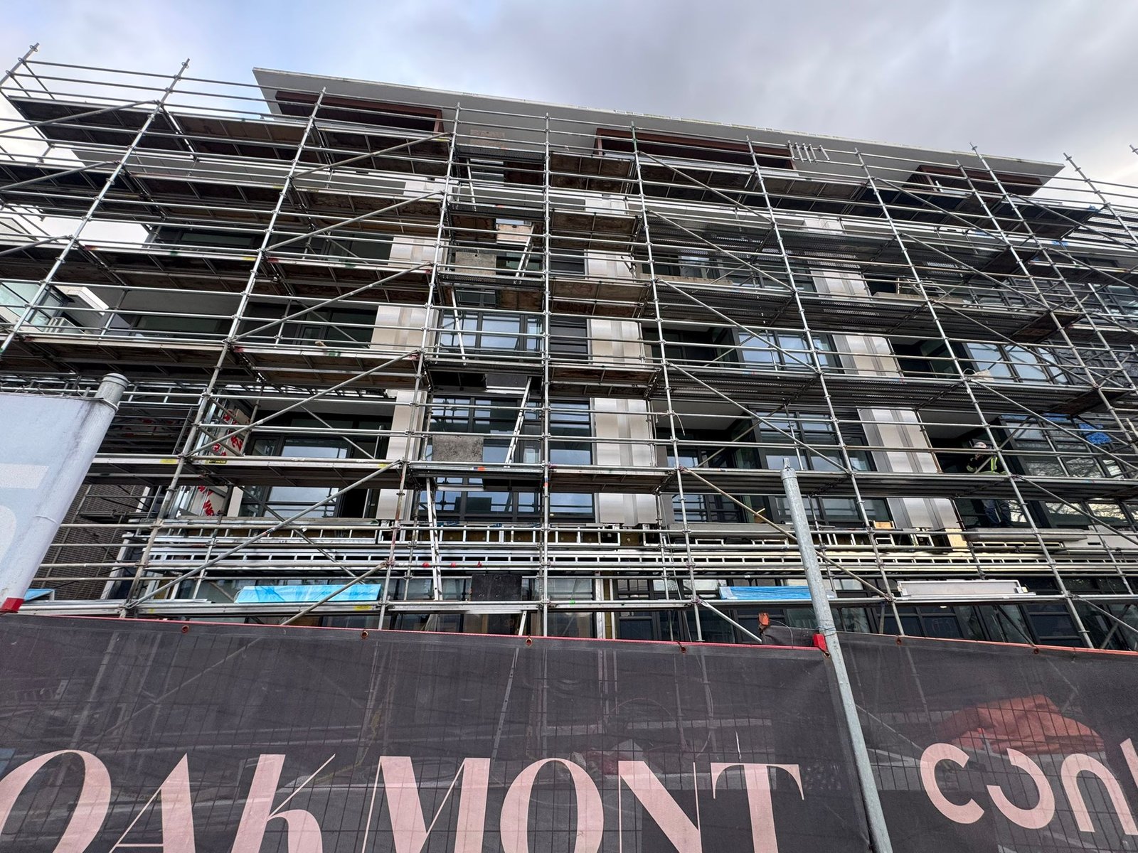North Side elevation under scaffolding — multi-storey exterior cladding in progress