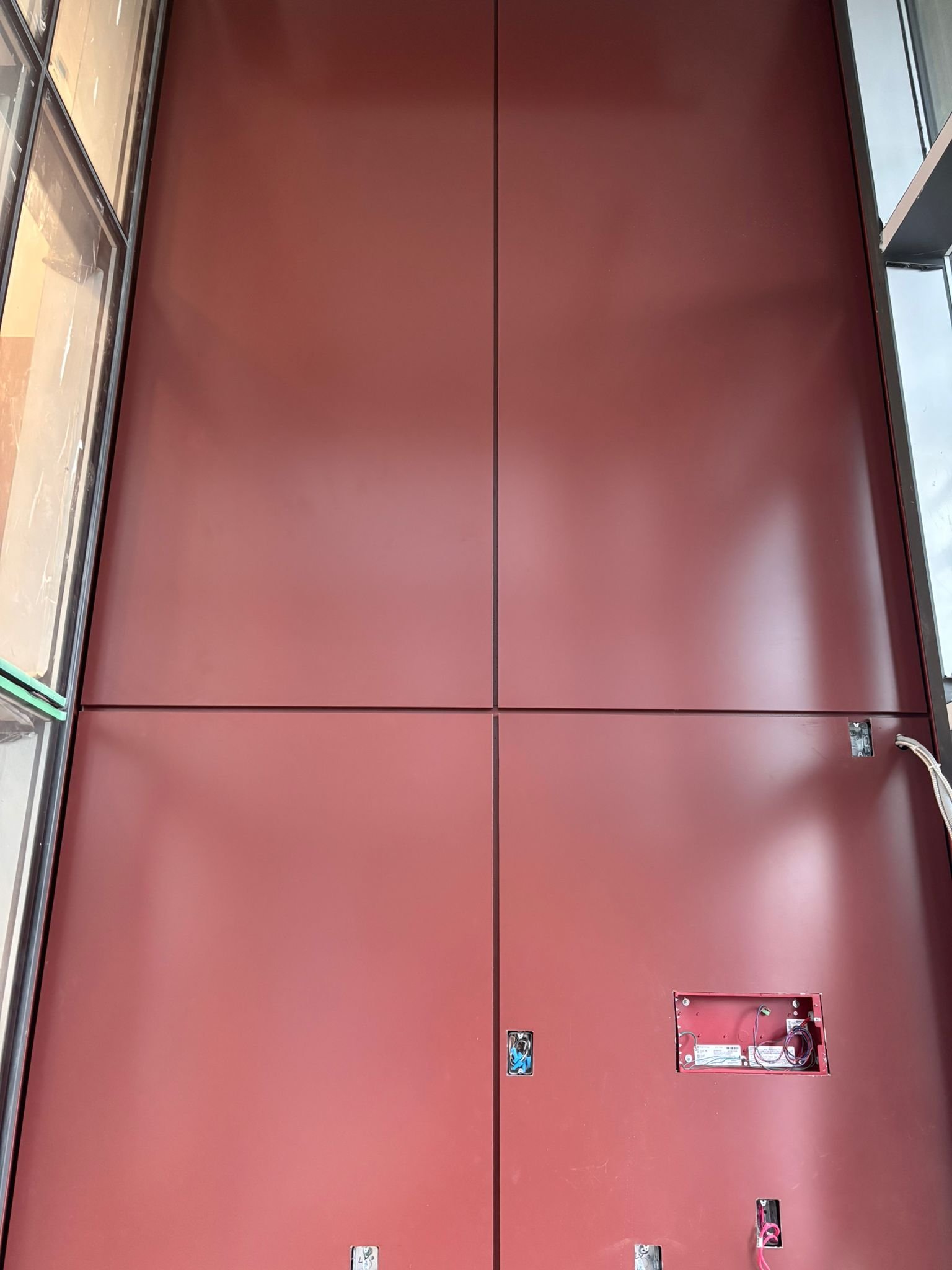 North Side deep-red ACM panel wall with recessed service boxes