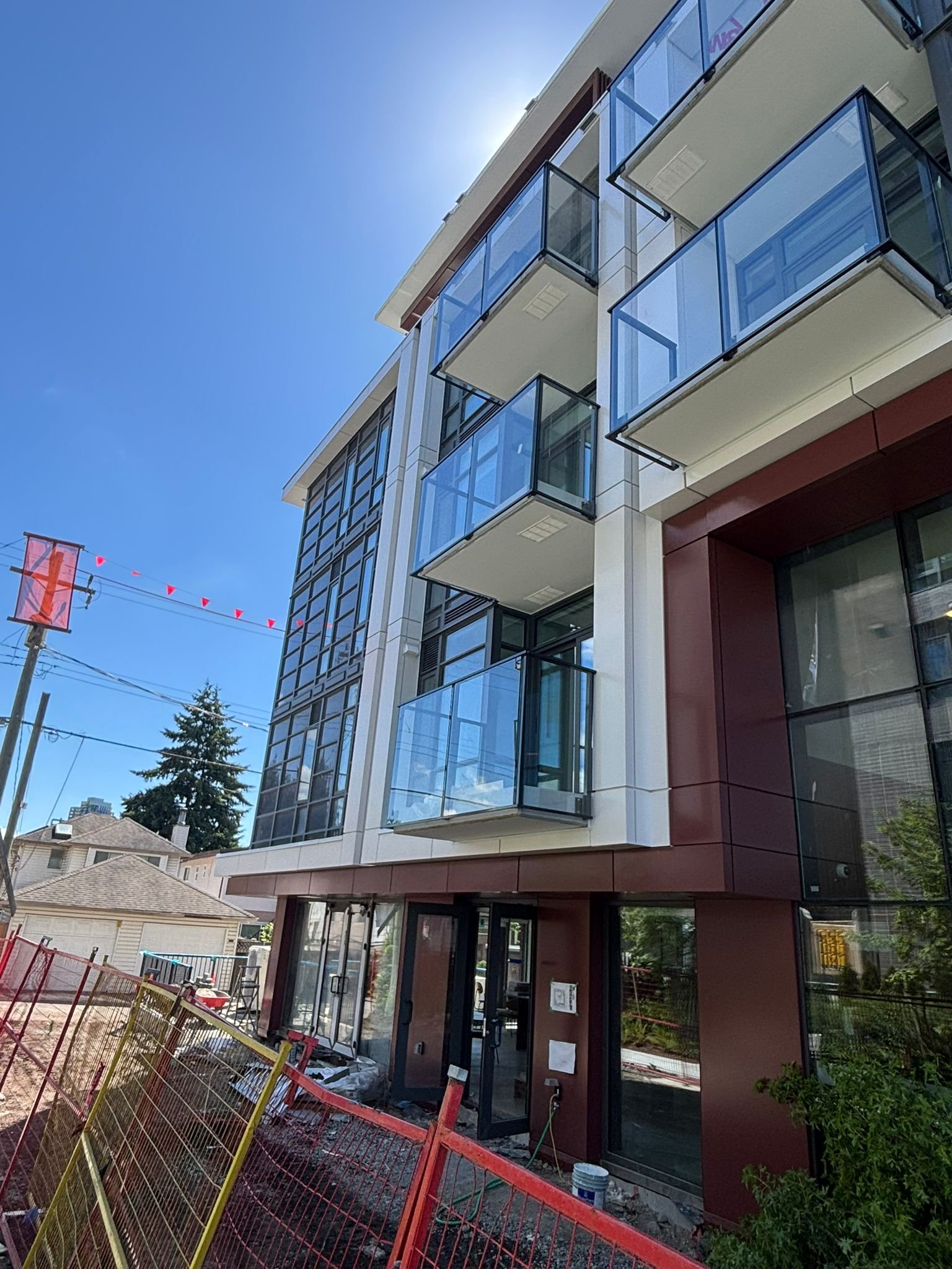 Oakmont podium entry framed by red ACM column cladding and glass balconies